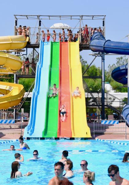 Piscina con scivoli colorati e persone che si divertono.