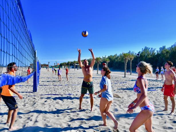 Folk spiller beachvolley på en solrig strand.