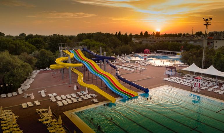 Wasserpark mit bunten Rutschen bei Sonnenuntergang.