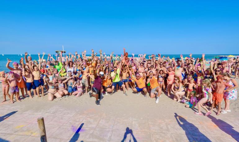 Gruppe von Menschen am Strand, die mit Begeisterung und lebendigen Farben feiern.