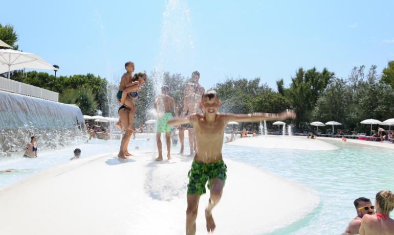 Menschen haben Spaß in einem Pool mit Wasserfontänen.