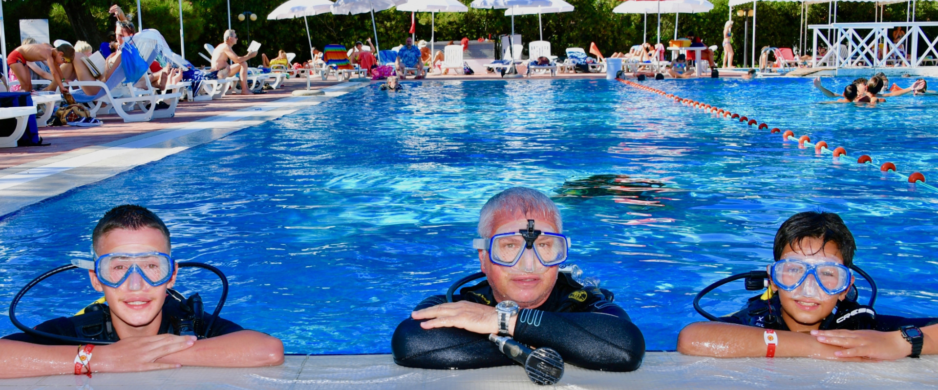 Persone con attrezzatura subacquea si rilassano in una piscina affollata.