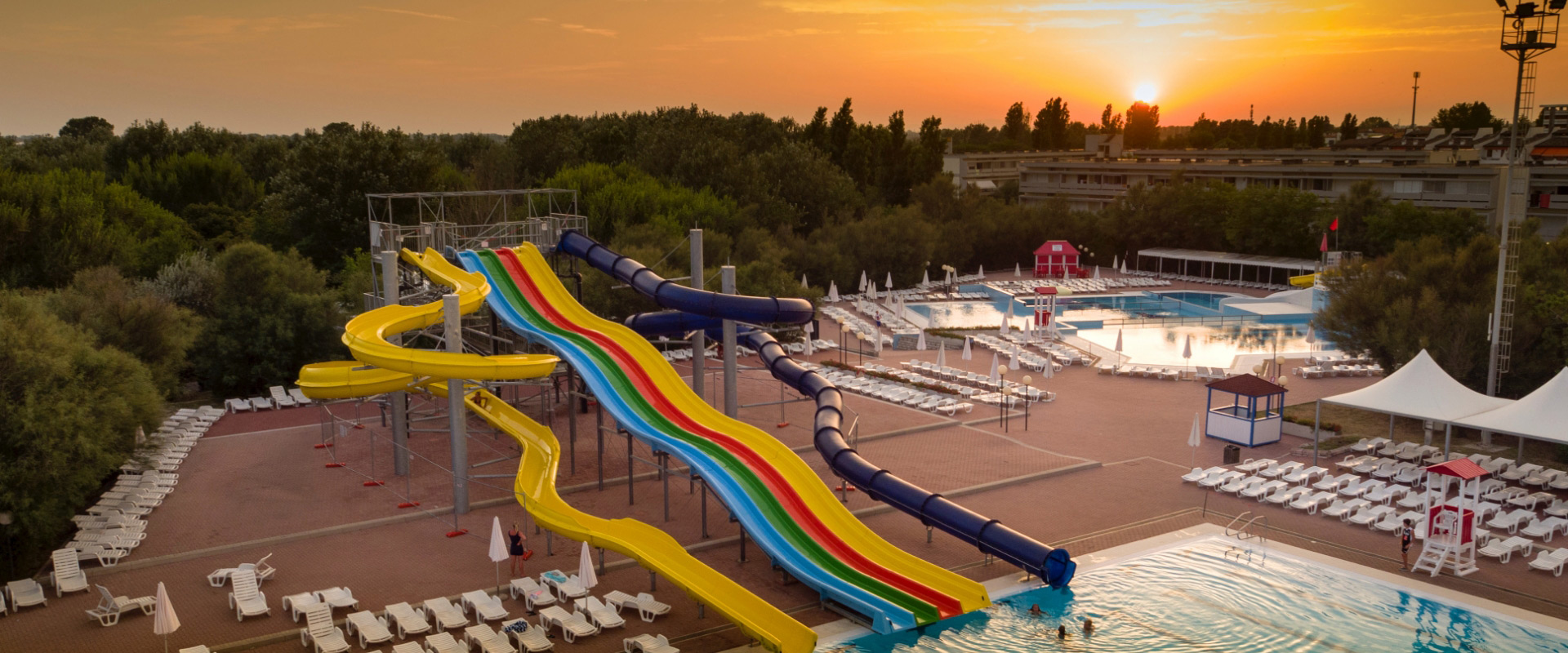 Parco acquatico con scivoli colorati e piscine al tramonto.