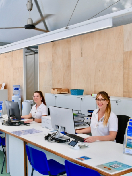 Due persone sorridenti lavorano al computer in un ufficio moderno e luminoso.