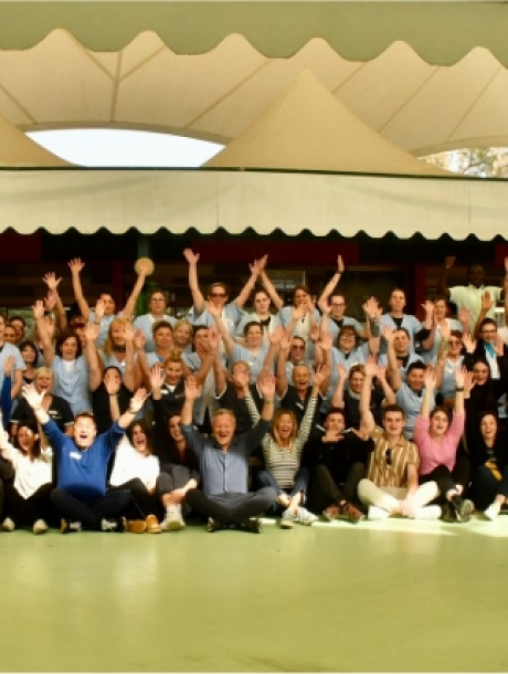 Gruppo di persone felici con le mani alzate, all'aperto sotto una tenda.