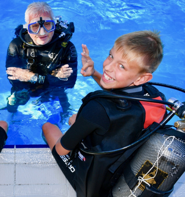 Due bambini e un adulto in piscina con attrezzatura da sub.