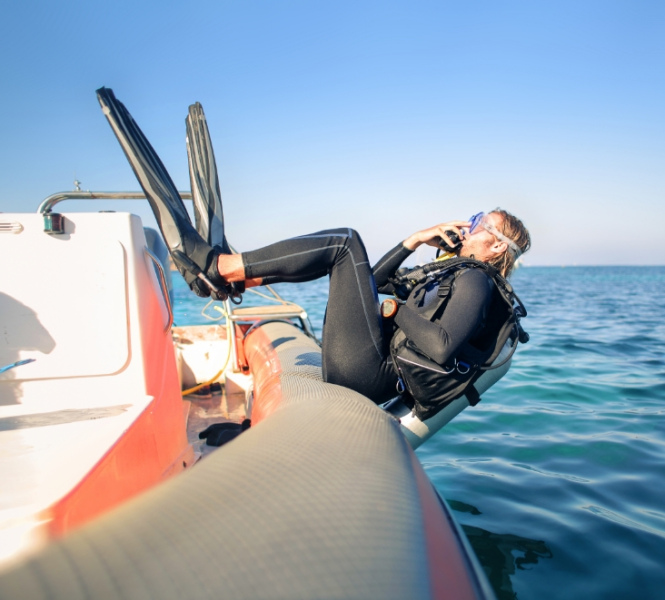 Subacqueo si tuffa in mare da un gommone, indossando attrezzatura da immersione.