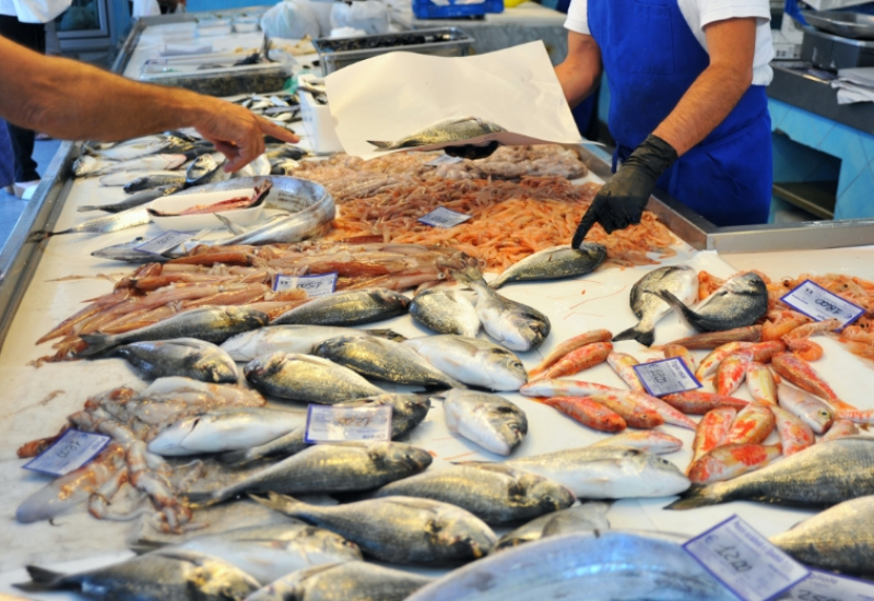 Banco del pesce in un mercato, con varietà di pesci e crostacei freschi.