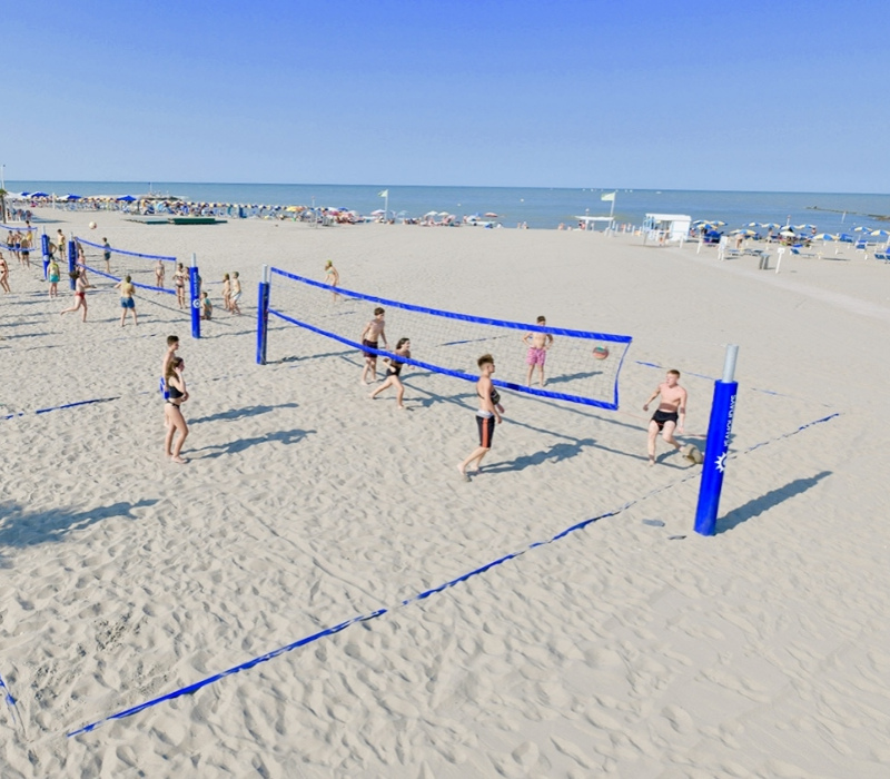 Spiaggia con campi da beach volley e persone che giocano sotto il sole.