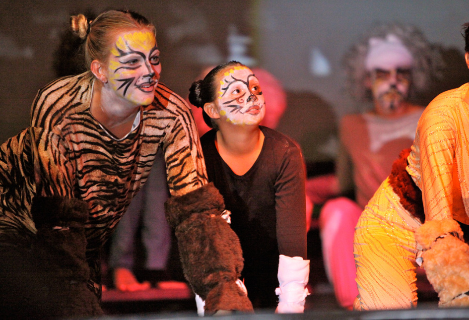 Persone in costumi e trucco da animali durante una performance teatrale.