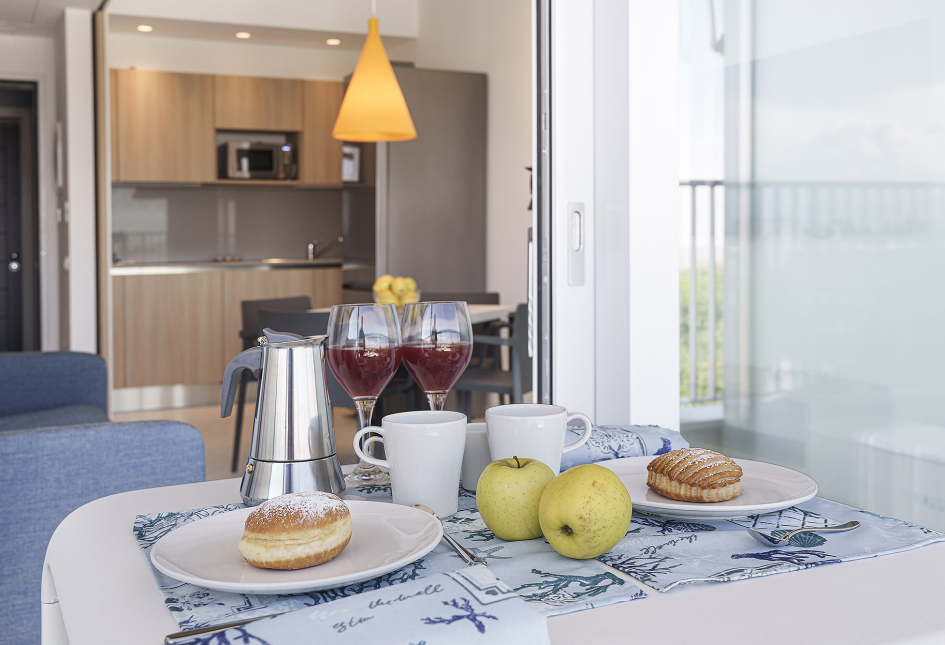 Colazione con caffè, dolci e mele in una cucina moderna con vista.