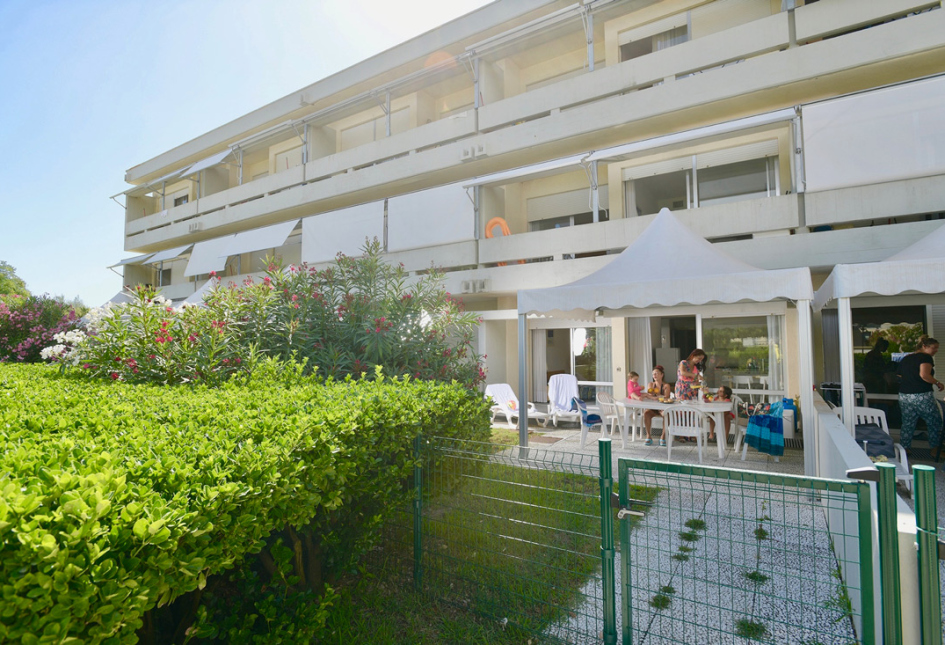 Edificio moderno con giardino e persone sedute sotto un gazebo bianco.