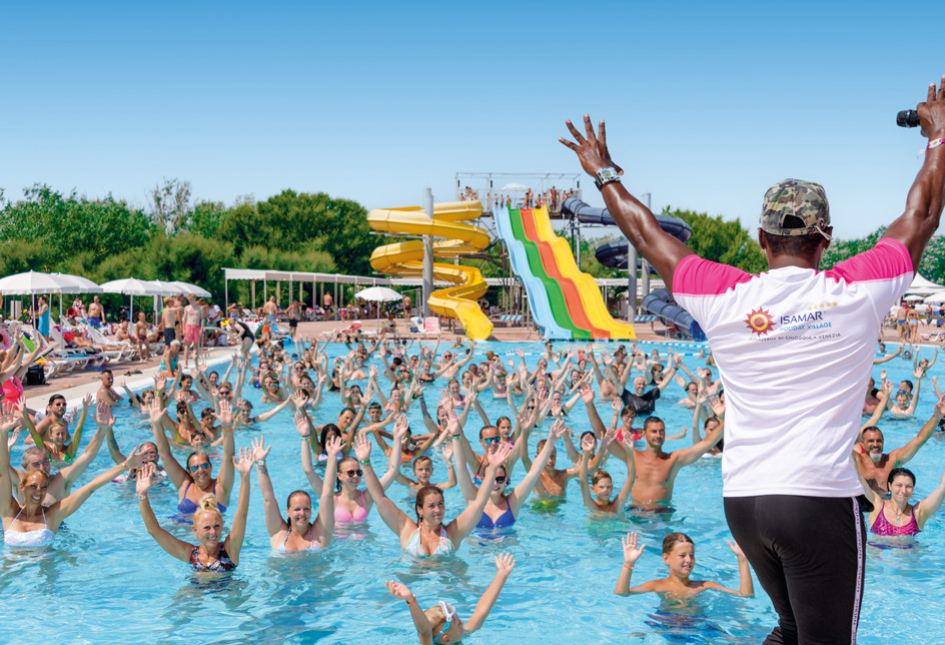 Animazione in piscina con scivoli colorati e partecipanti sorridenti al villaggio turistico.